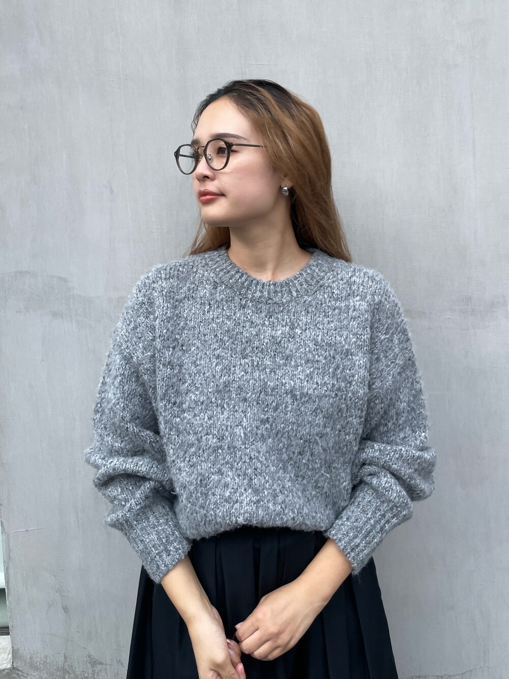 グレー系のニット/セーター、ブラック系のスカートを着用したレディースの秋コーディネートの3枚目の写真