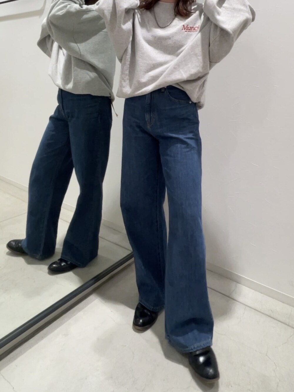 グレー系のスウェット、ブルー系のデニムパンツ、シルバー系のネックレスを着用したレディースの冬コーディネートの3枚目の写真
