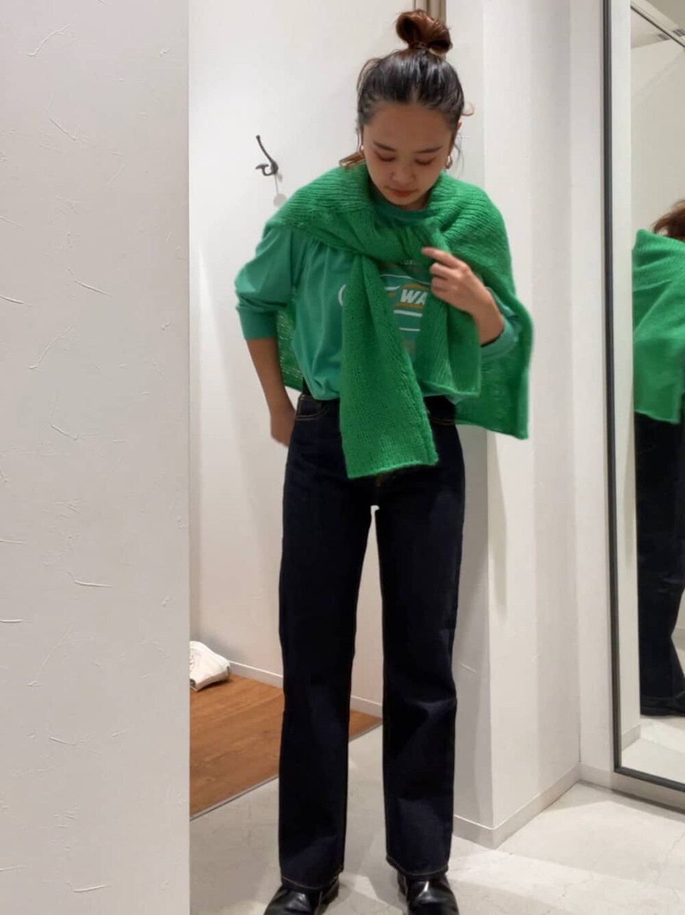 グリーン系のニット/セーター、グリーン系のTシャツ/カットソー、ブルー系のデニムパンツを着用したレディースの秋コーディネートの2枚目の写真