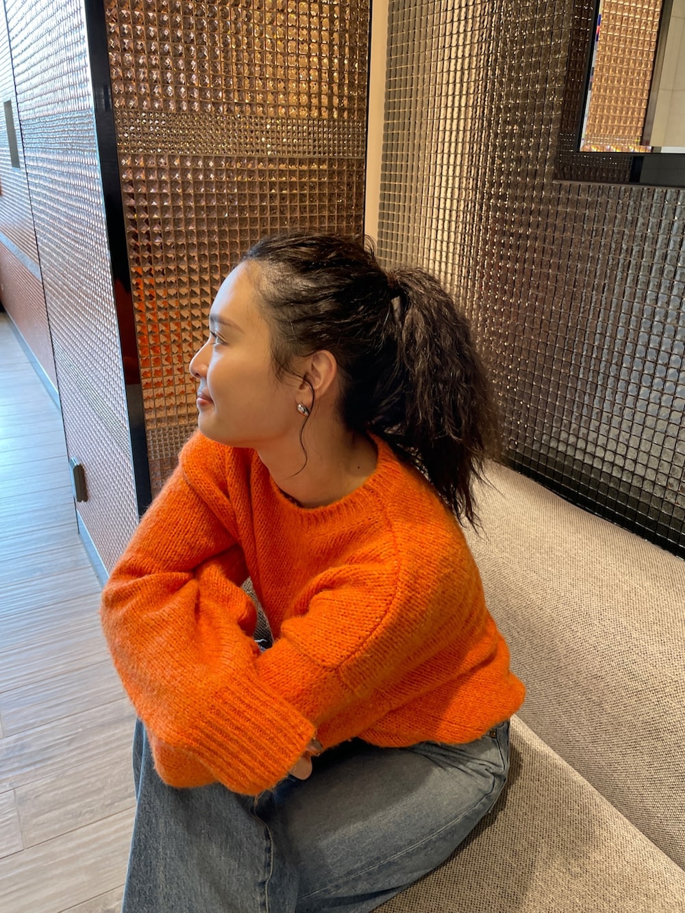 ブルー系のデニムパンツ、ブラック系のブーツ、オレンジ系のニット/セーターを着用したレディースの秋コーディネートの4枚目の写真