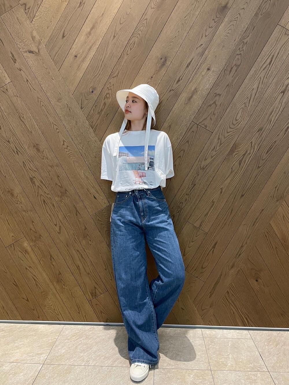 ブルー系のデニムパンツ、ホワイト系のスニーカー、グレー系のTシャツ/カットソーを着用したレディースの春コーディネートの4枚目の写真