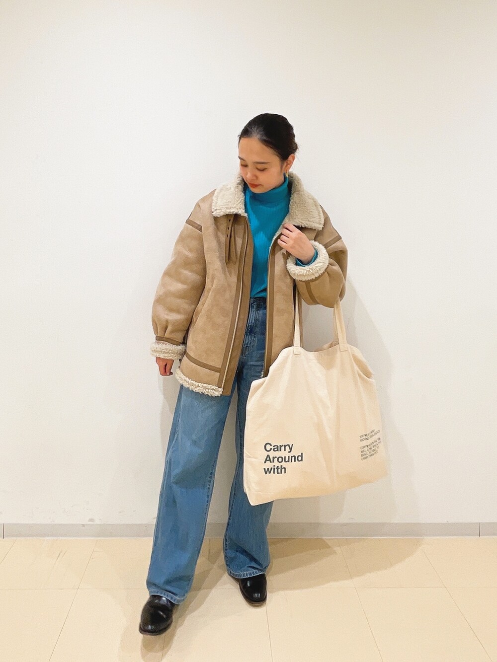 ベージュ系のムートンコート、ブルー系のニット/セーター、ホワイト系のハンドバッグを着用したレディースの冬コーディネートの8枚目の写真