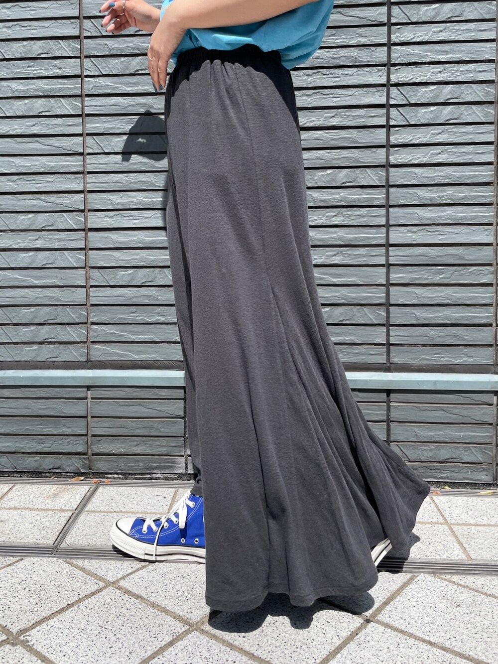 ブルー系のTシャツ/カットソー、グレー系のスカート、ブルー系のスニーカーを着用したレディースの春コーディネートの5枚目の写真