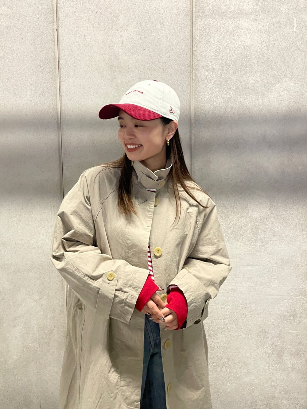 ブルー系のデニムパンツ、ベージュ系のステンカラーコート、レッド系のTシャツ/カットソーを着用したレディースの冬コーディネートの3枚目の写真