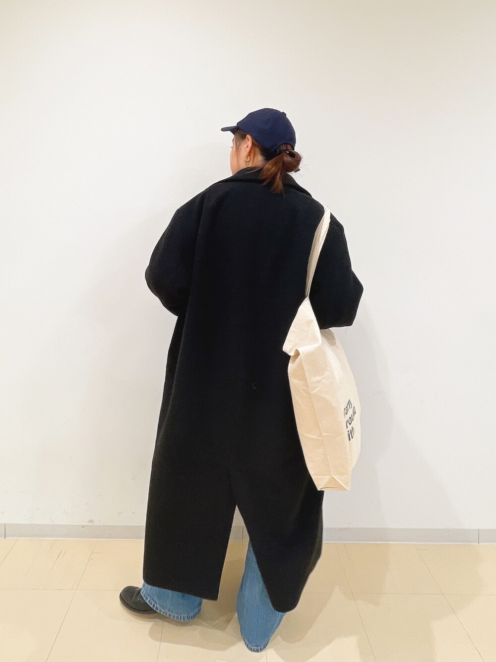 イエロー系のニット/セーター、ホワイト系のハンドバッグ、ブルー系のデニムパンツを着用したレディースの冬コーディネートの7枚目の写真