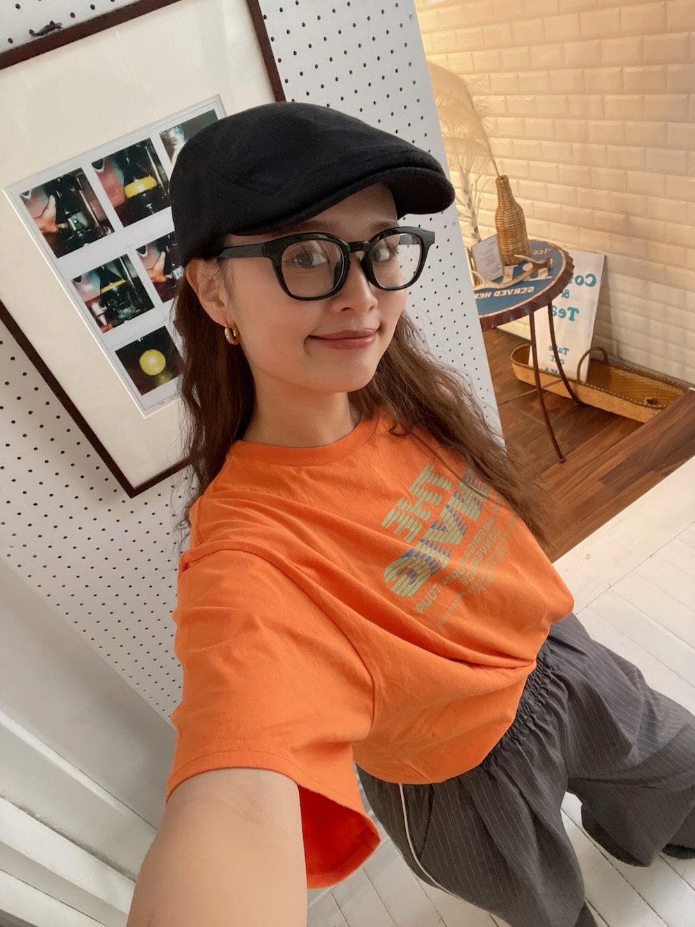 オレンジ系のTシャツ/カットソー、グレー系のその他パンツ、ブラック系のハンチング/ベレー帽を着用したレディースの春コーディネートの2枚目の写真