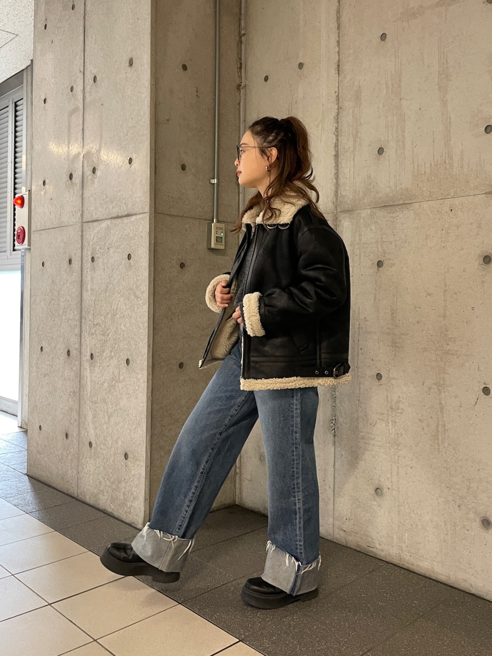 ブラック系のムートンコート、ブルー系のデニムパンツ、グレー系のニット/セーターを着用したレディースの冬コーディネートの8枚目の写真