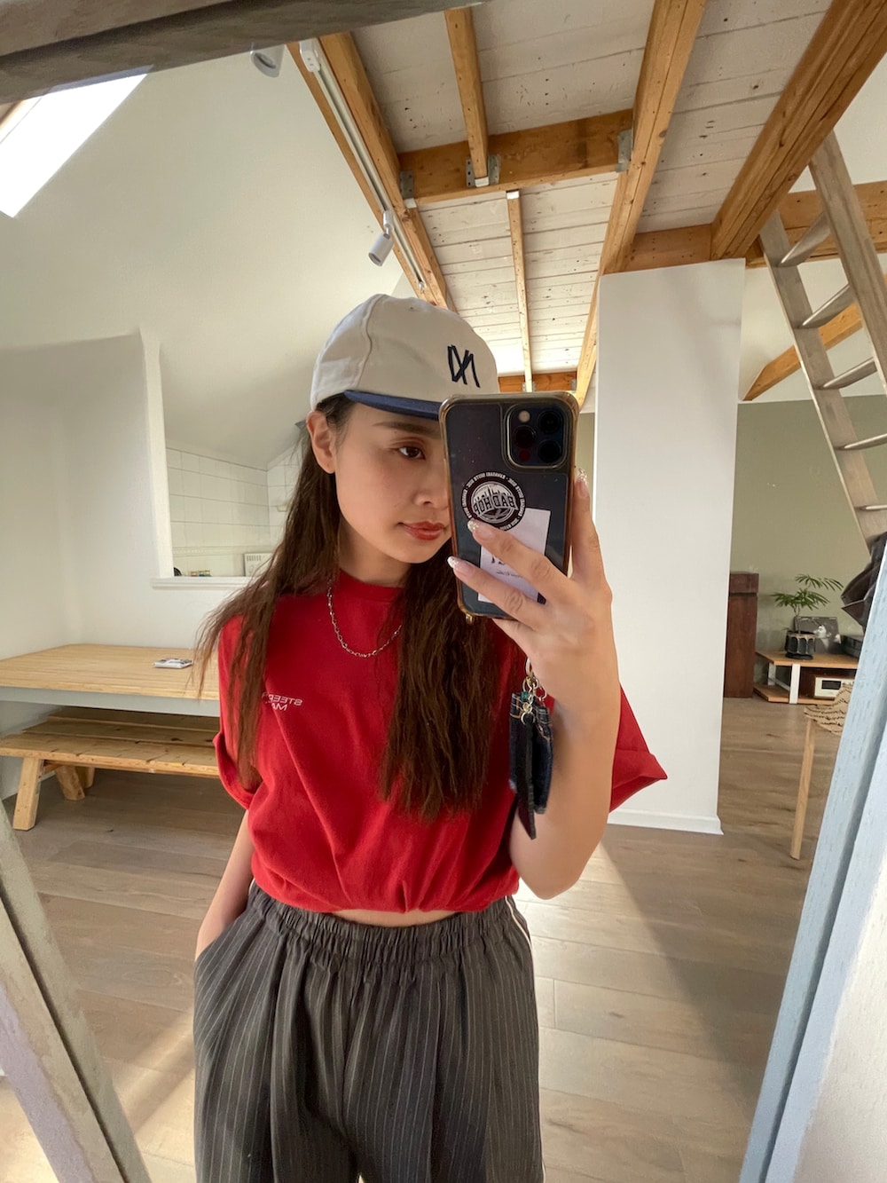 グレー系のその他パンツ、レッド系のTシャツ/カットソー、ホワイト系のキャップを着用したレディースの春コーディネートの2枚目の写真