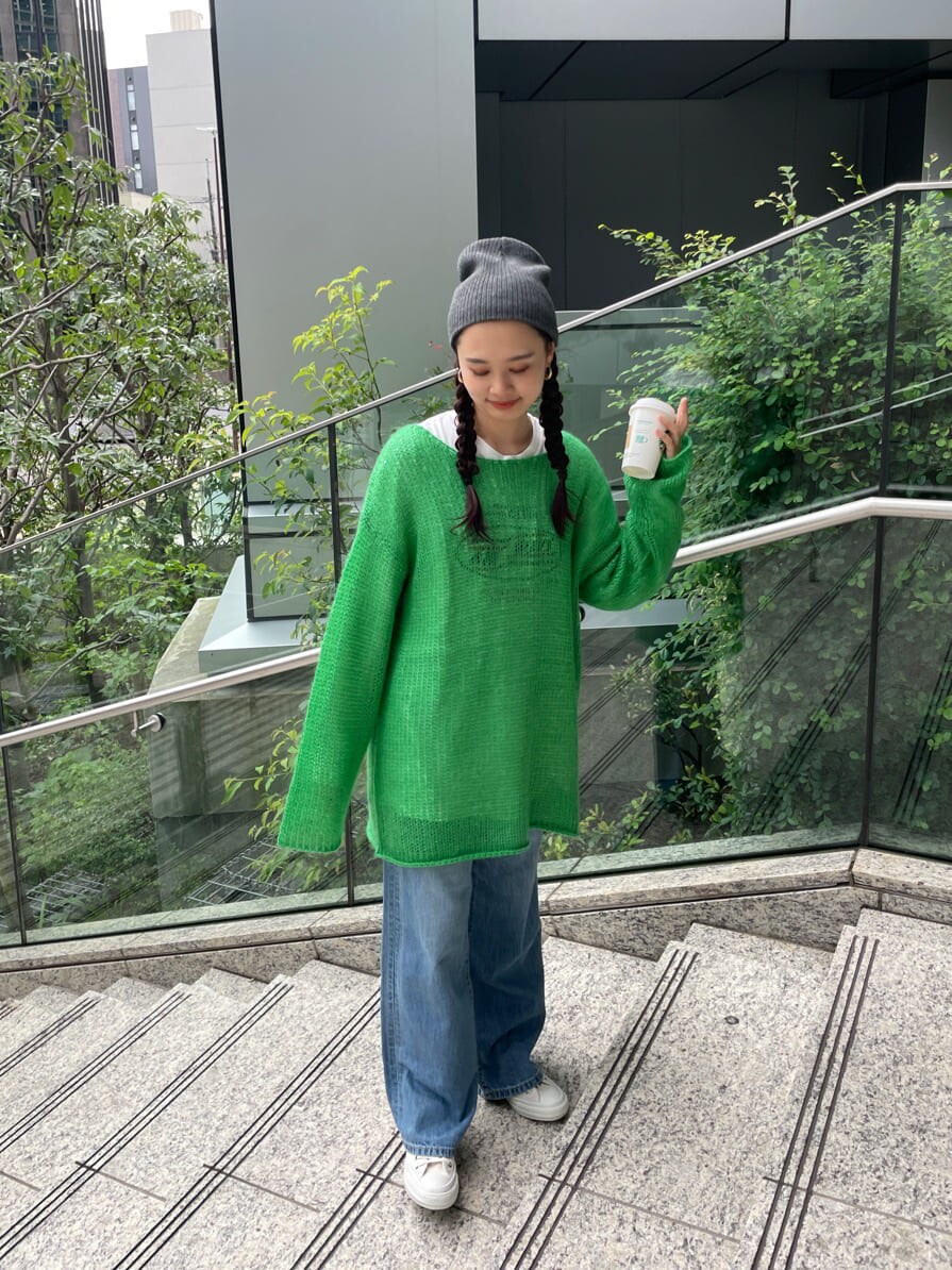 ブルー系のデニムパンツ、ホワイト系のTシャツ/カットソー、グリーン系のニット/セーターを着用したレディースの秋コーディネートの3枚目の写真