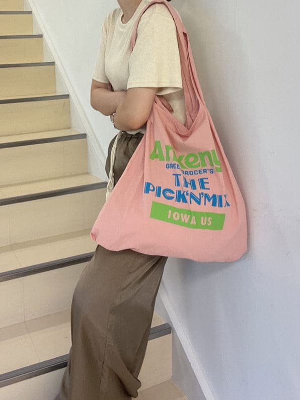 ピンク系のエコバッグ/サブバッグ、ブラウン系のその他パンツ、ホワイト系のTシャツ/カットソーを着用したレディースの夏コーディネートの3枚目の写真