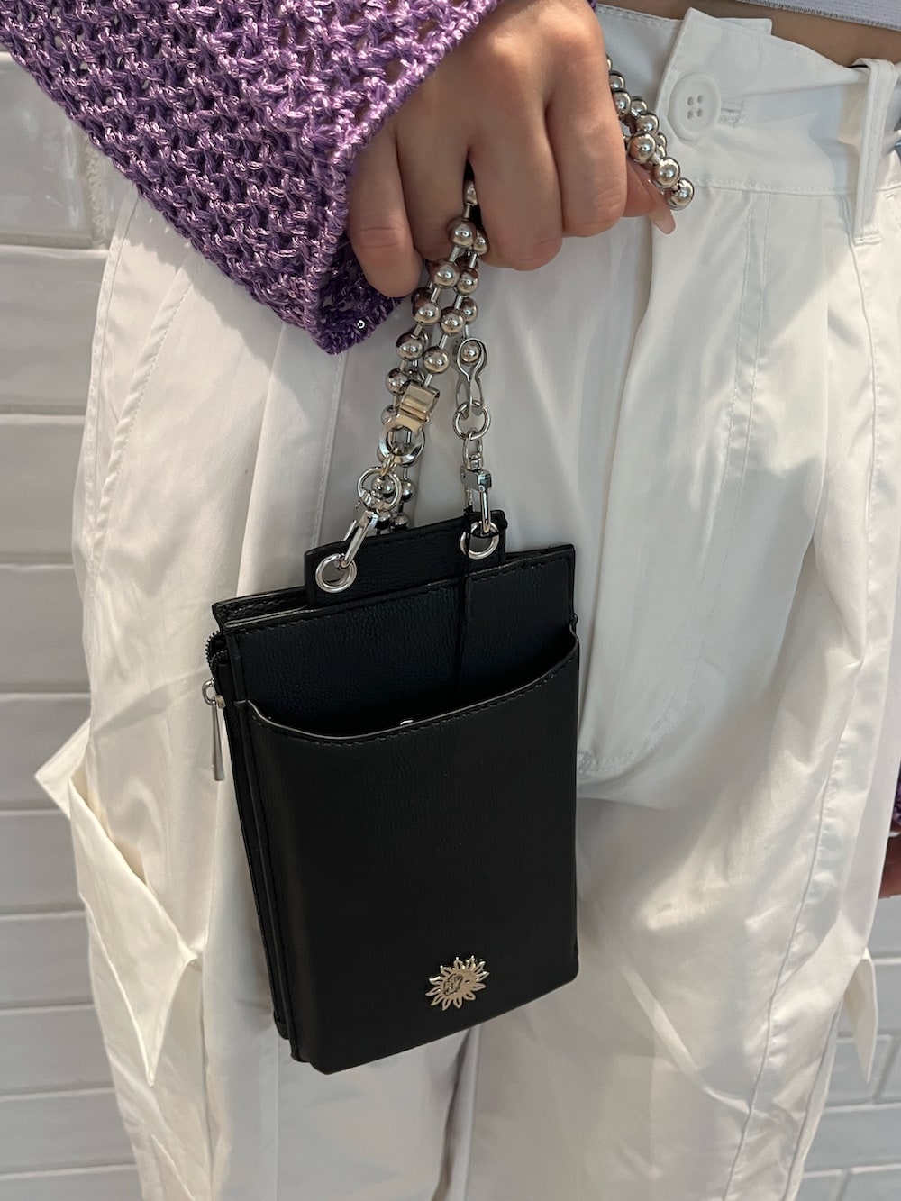 パープル系のニット/セーター、ブラック系のキャミソール、ブラック系のショルダーバッグを着用したレディースの春コーディネートの8枚目の写真