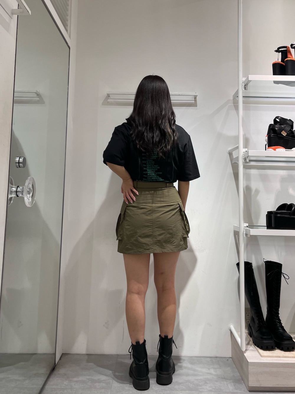 ブラック系のTシャツ/カットソー、グリーン系のスカート、ブラック系のブーツを着用したレディースの夏コーディネートの2枚目の写真