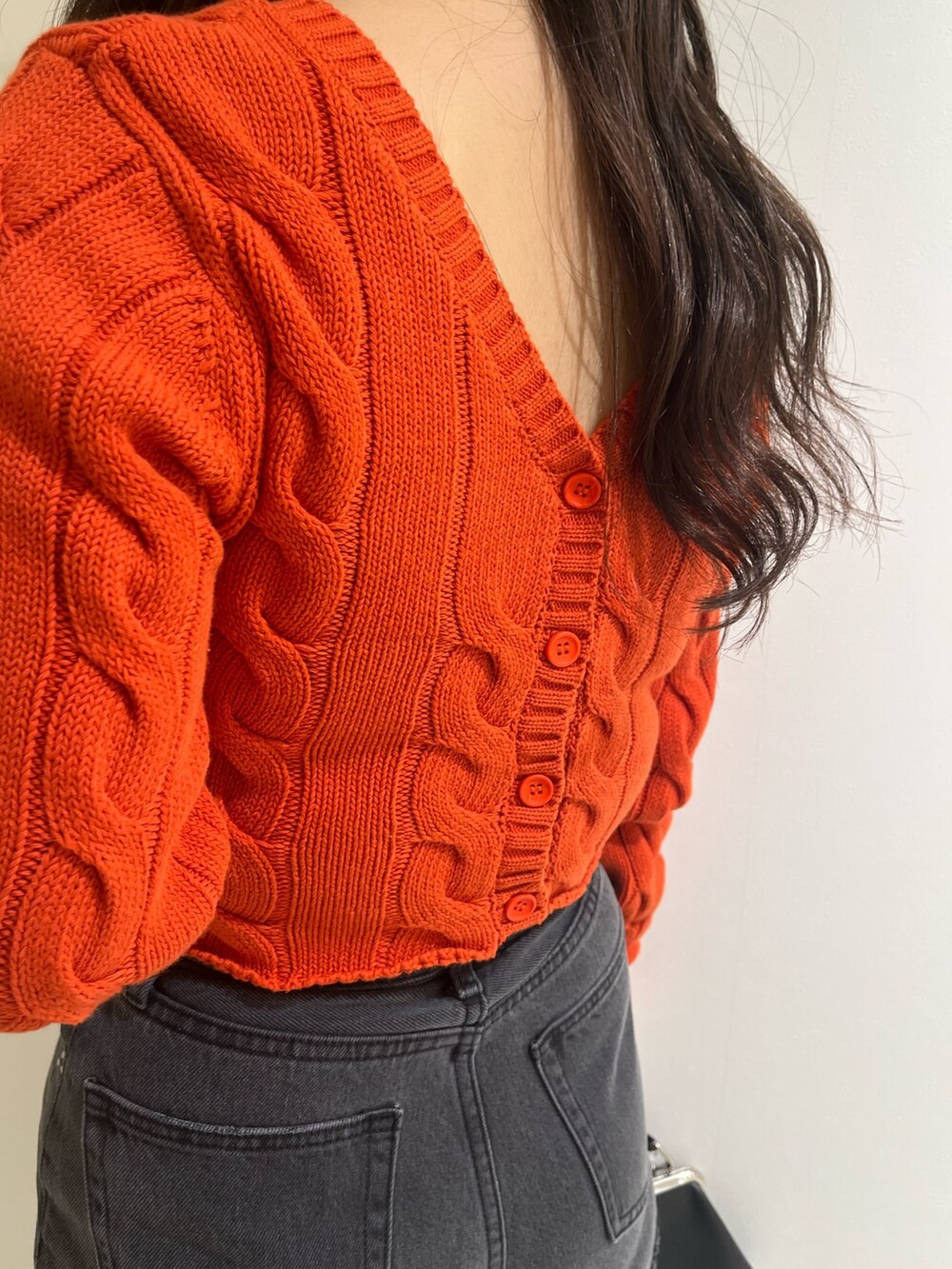 オレンジ系のカーディガン/ボレロ、ブラック系のデニムパンツ、ブラック系のショルダーバッグを着用したレディースの冬コーディネートの6枚目の写真