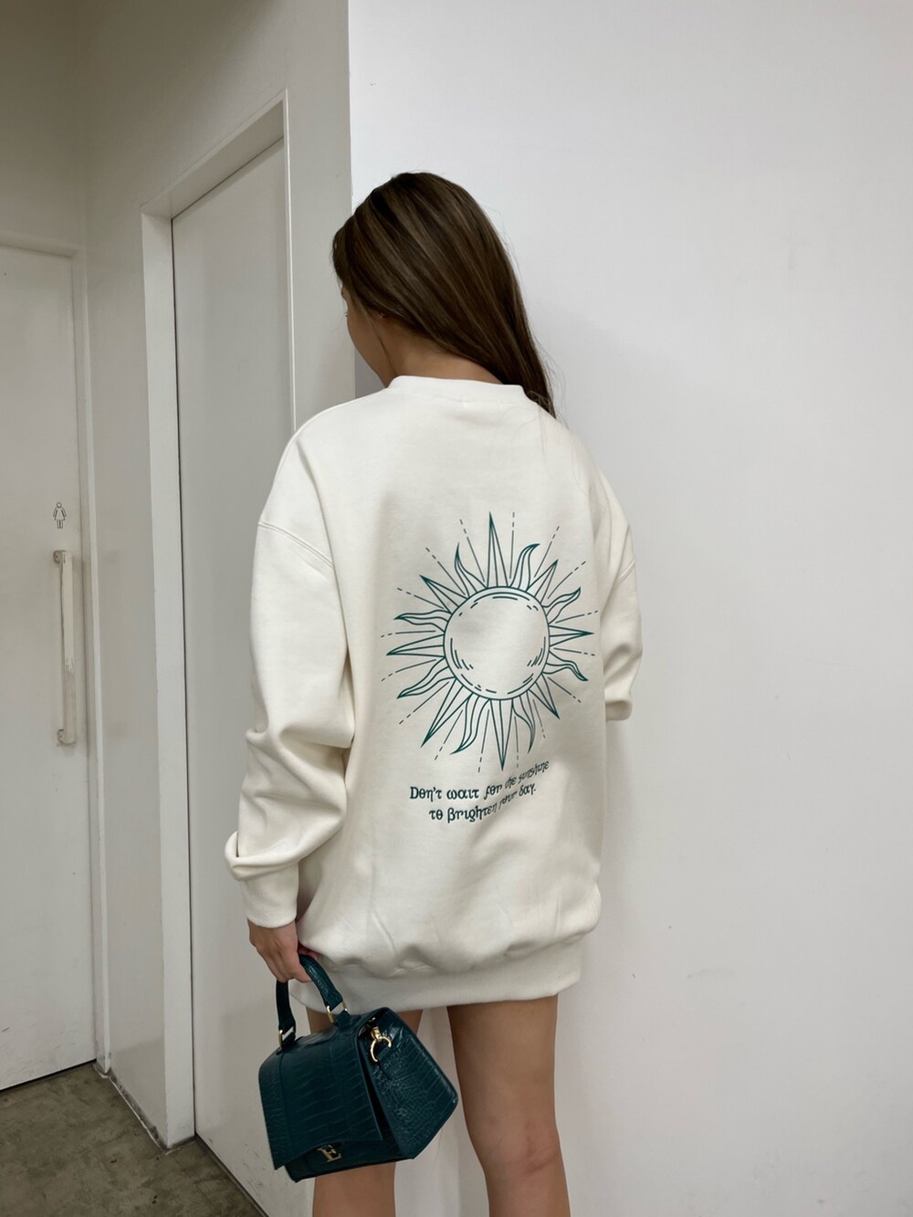 ホワイト系のスウェット、ブラック系のデニムスカート、ブラック系のブーツを着用したレディースの秋コーディネートの2枚目の写真