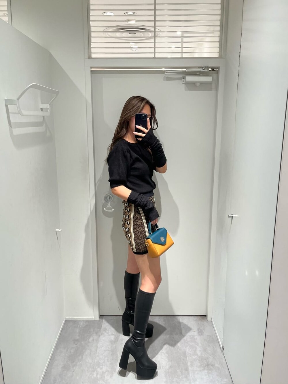 ブラック系のスカート、ブラック系のブーツ、ブラック系のニット/セーターを着用したレディースの秋コーディネートの2枚目の写真