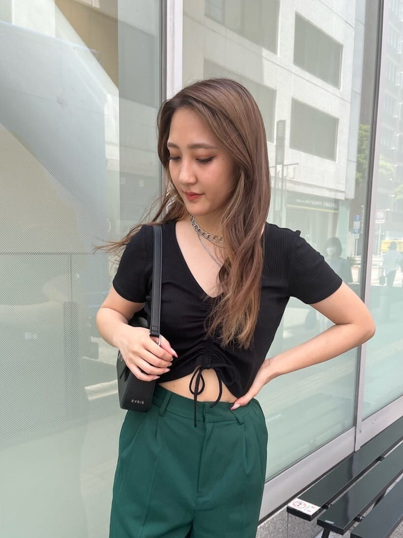 グリーン系のスラックス、ブラック系のショルダーバッグ、ブラック系のTシャツ/カットソーを着用したレディースの夏コーディネートの3枚目の写真