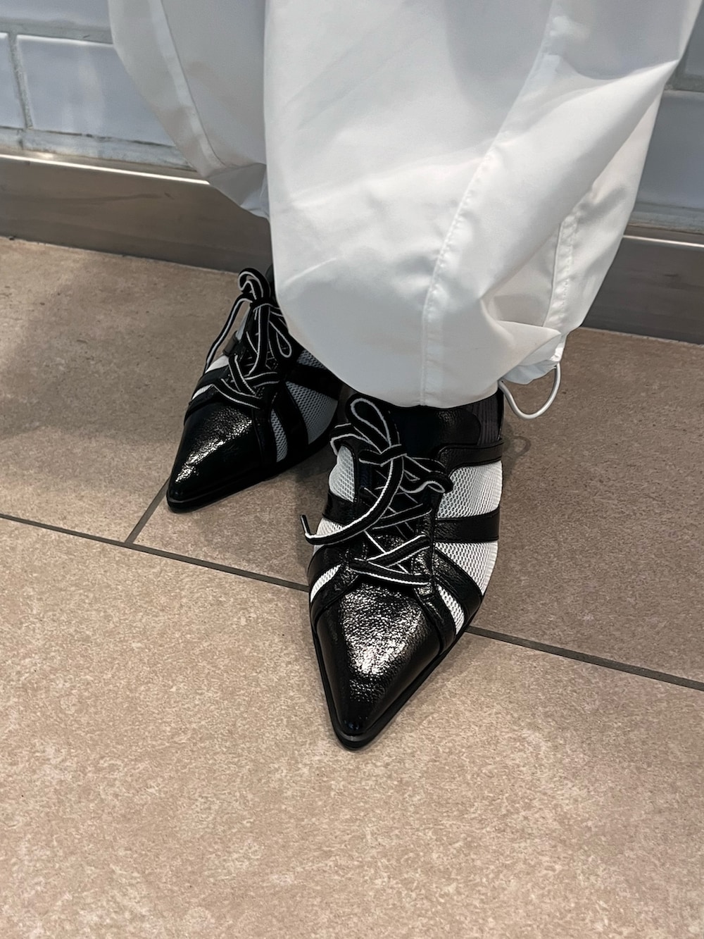 パープル系のニット/セーター、ブラック系のキャミソール、ブラック系のショルダーバッグを着用したレディースの春コーディネートの7枚目の写真