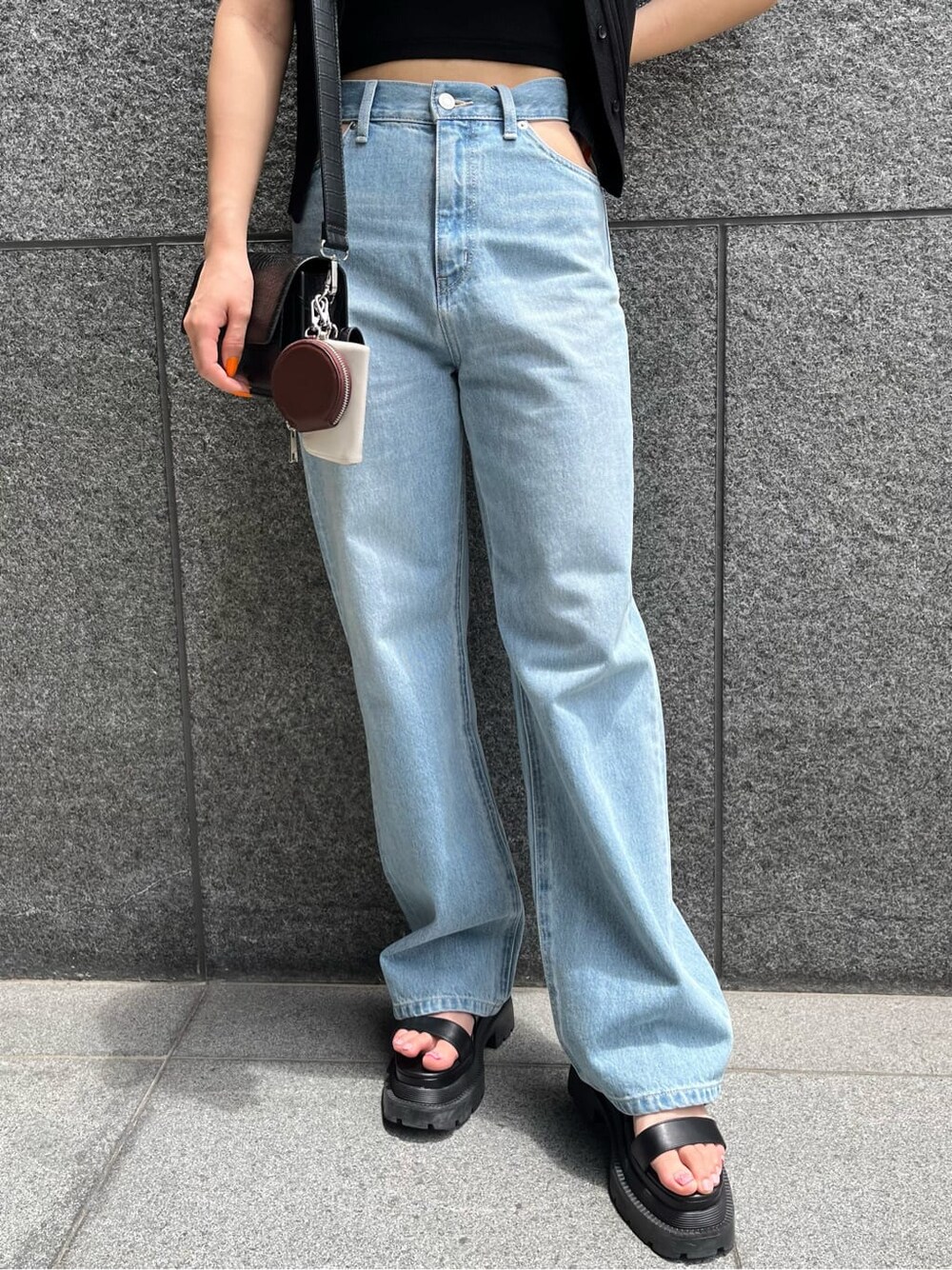 ブラック系のショルダーバッグ、ブルー系のデニムパンツ、ブラック系のニット/セーターを着用したレディースの夏コーディネートの6枚目の写真