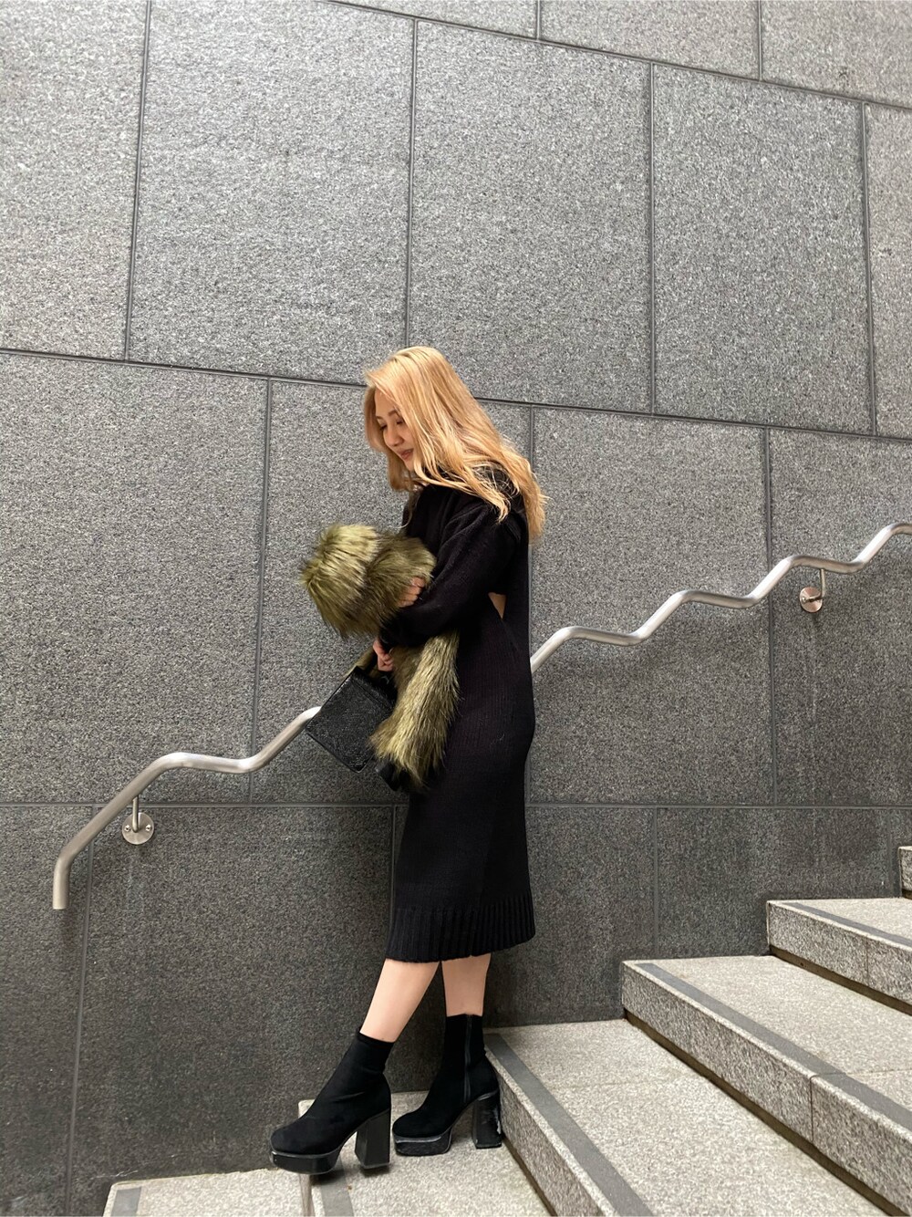 ブラック系のハンドバッグ、ブラック系のワンピースを着用したレディースの冬コーディネートの4枚目の写真