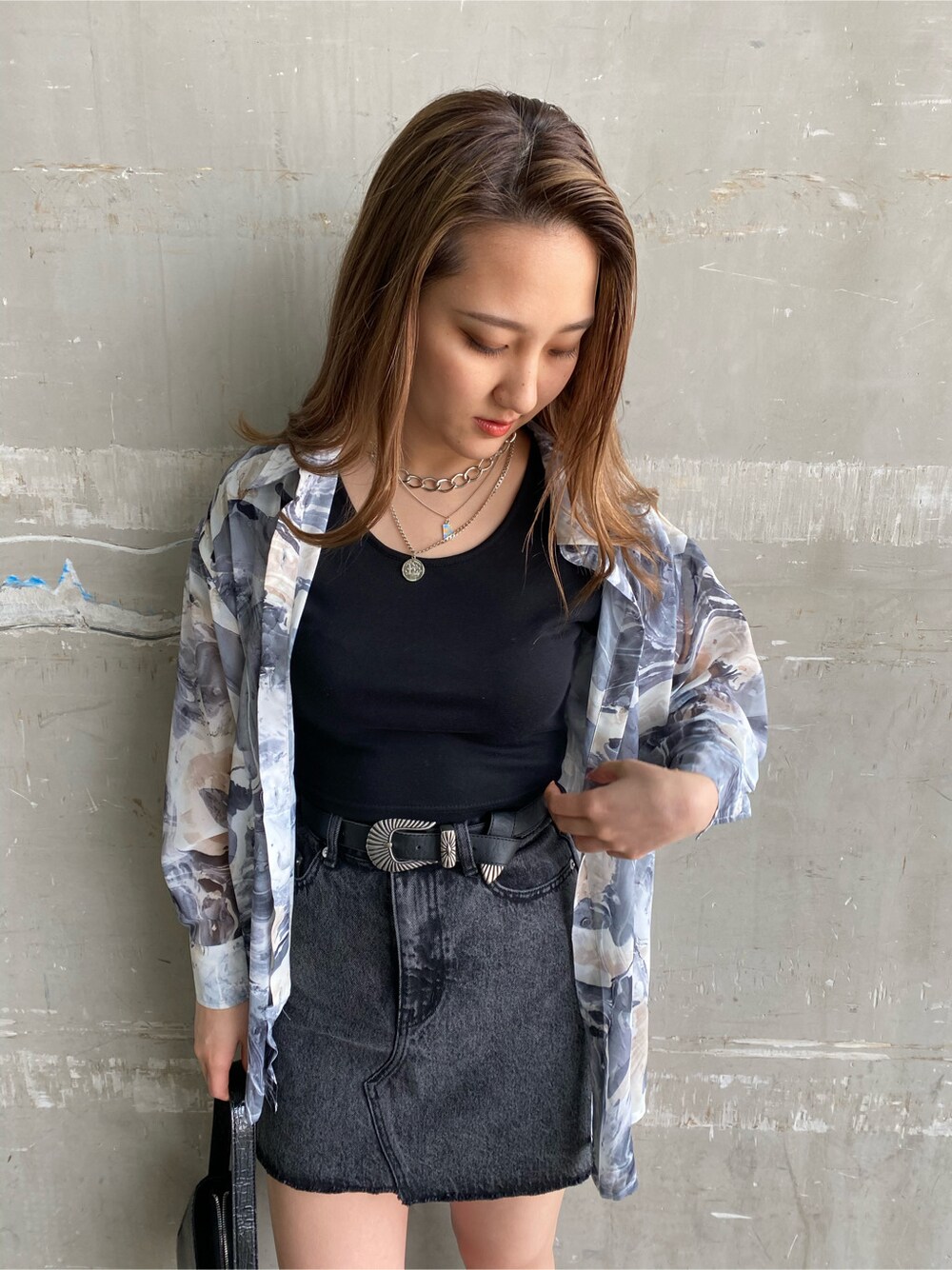 ブラック系のTシャツ/カットソー、ブラック系のデニムスカート、ブラック系のショルダーバッグを着用したレディースの春コーディネートの4枚目の写真