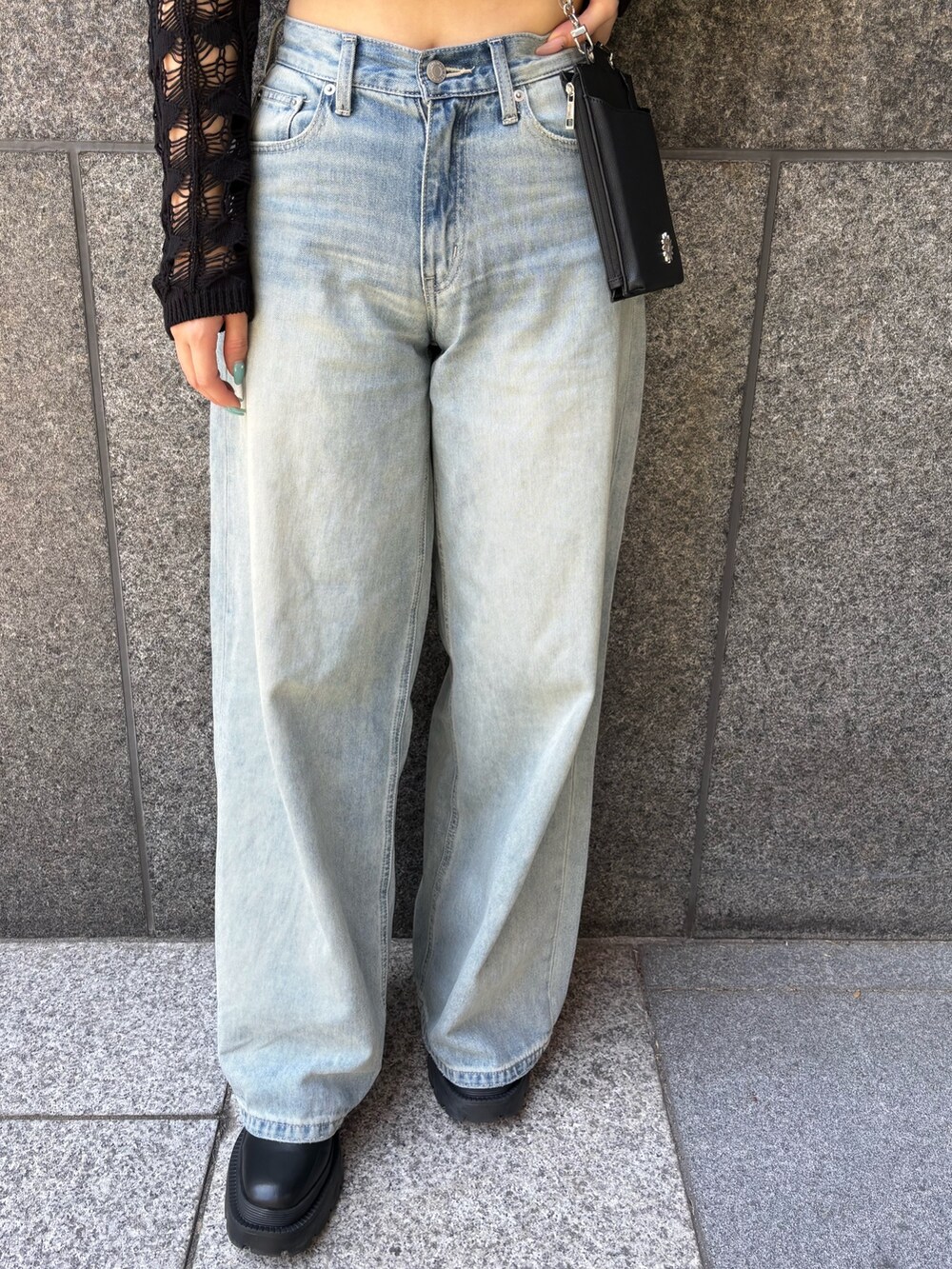 ブラック系のニット/セーター、ブラック系のキャミソール、ブルー系のデニムパンツを着用したレディースの春コーディネートの4枚目の写真