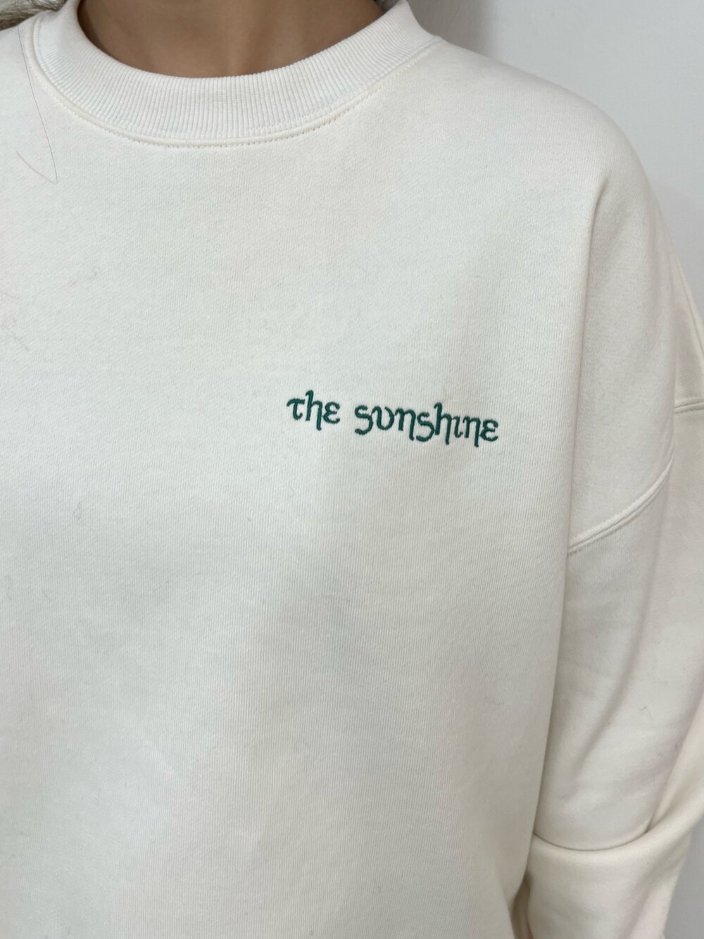 ホワイト系のスウェット、ブラック系のデニムスカート、ブラック系のブーツを着用したレディースの秋コーディネートの5枚目の写真