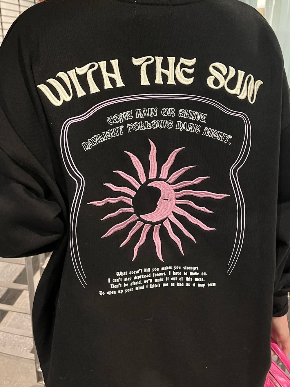 ブラック系のスウェット、ピンク系のショルダーバッグ、ブラック系のブーツを着用したレディースの冬コーディネートの4枚目の写真