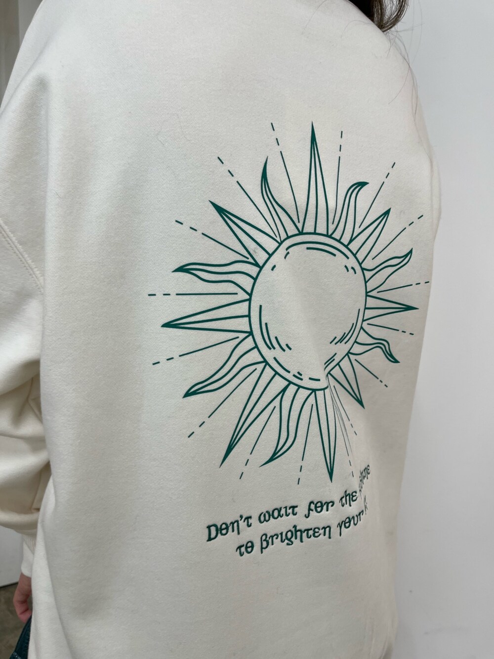 ホワイト系のスウェット、ブラック系のデニムスカート、ブラック系のブーツを着用したレディースの秋コーディネートの4枚目の写真