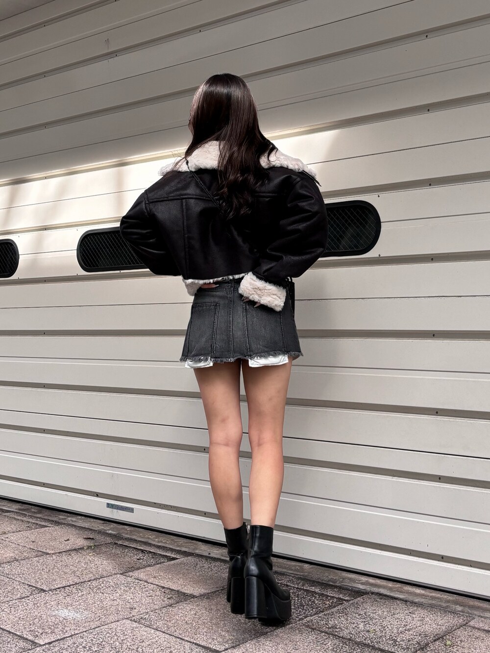 ブラック系のブルゾン、グレー系のニット/セーター、ブラック系のデニムスカートを着用したレディースの冬コーディネートの3枚目の写真