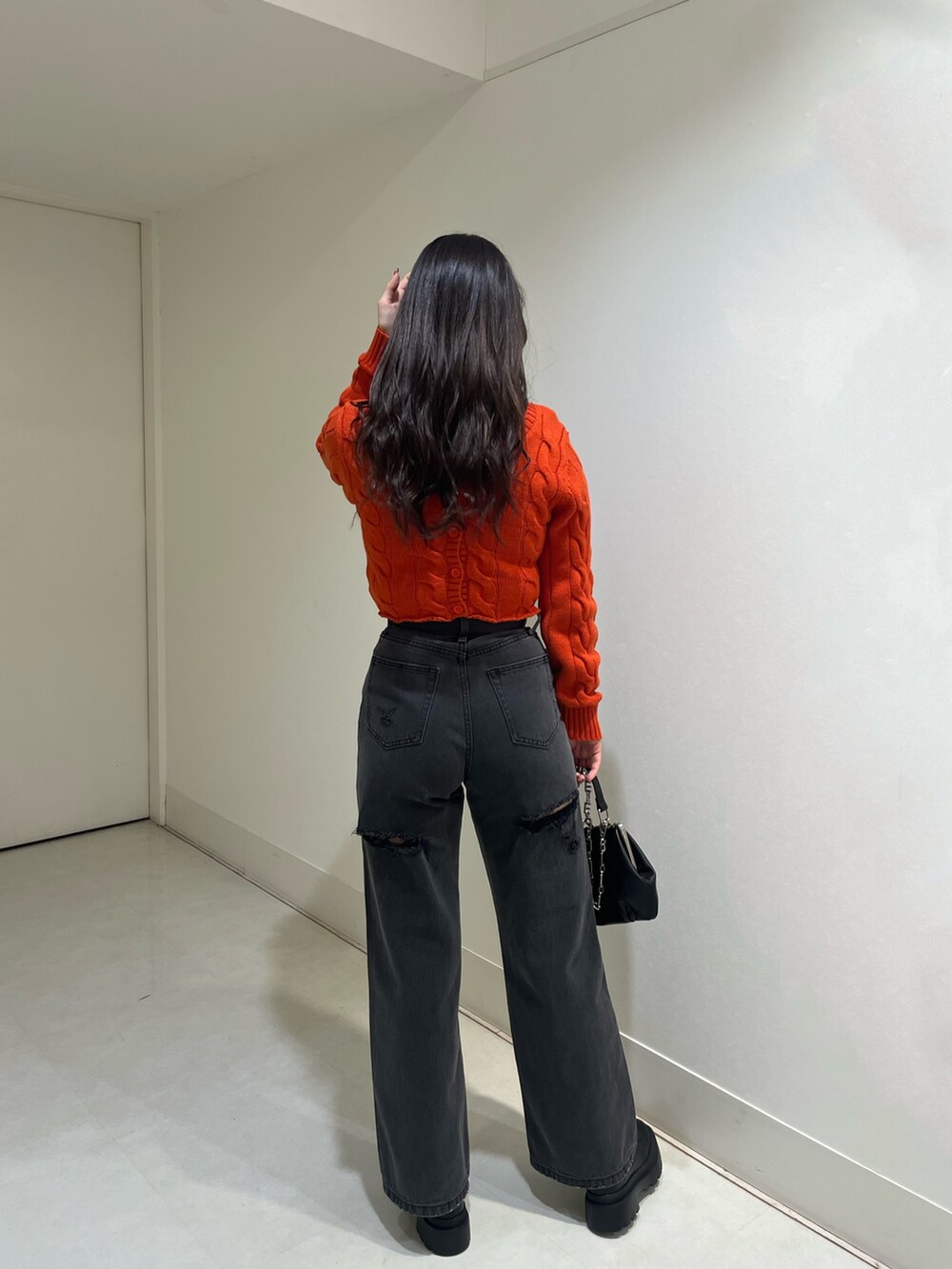 オレンジ系のカーディガン/ボレロ、ブラック系のデニムパンツ、ブラック系のショルダーバッグを着用したレディースの冬コーディネートの2枚目の写真