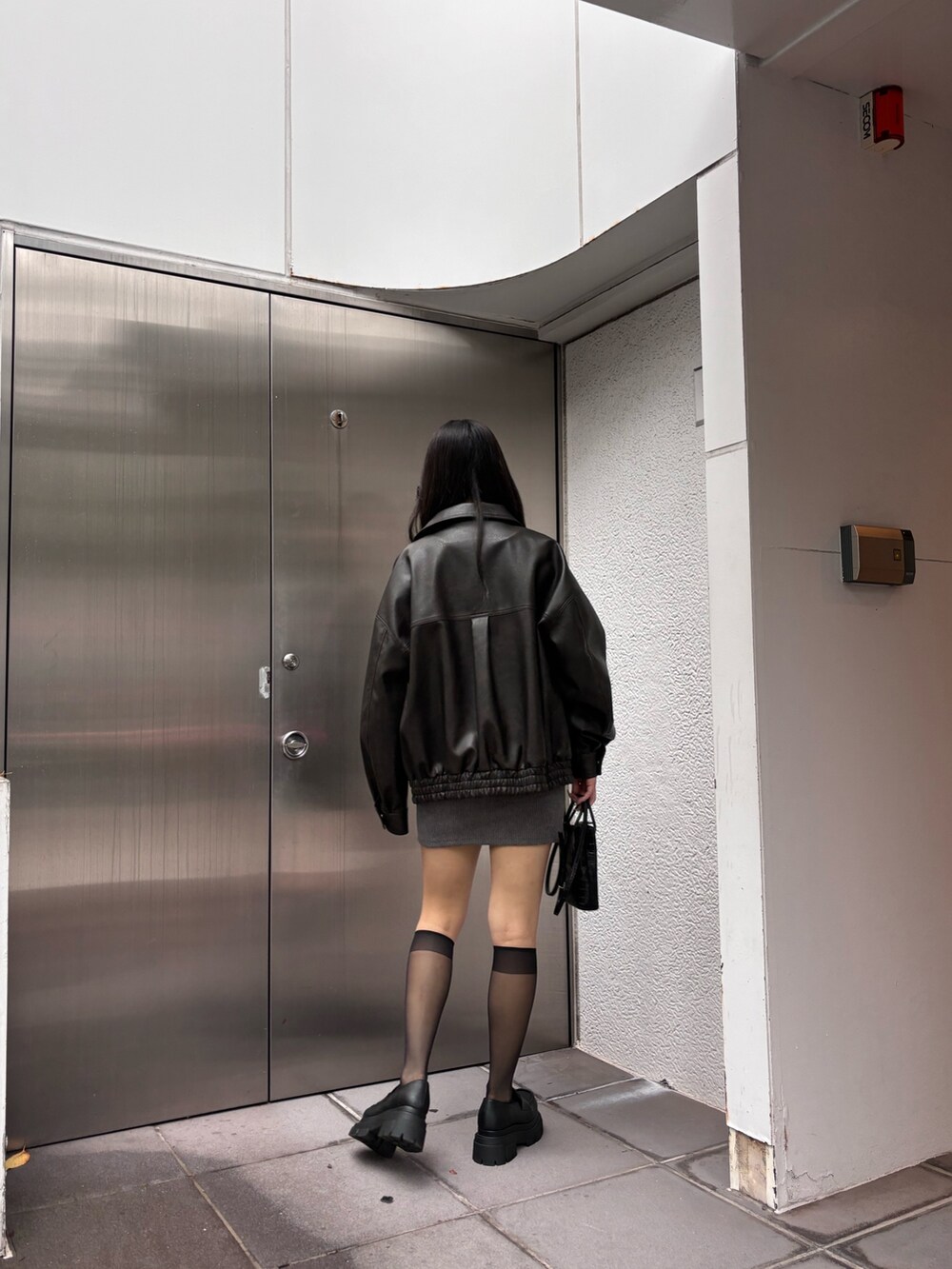 ブラウン系のブルゾン、ブラック系のローファー、グレー系のワンピースを着用したレディースの秋コーディネートの3枚目の写真