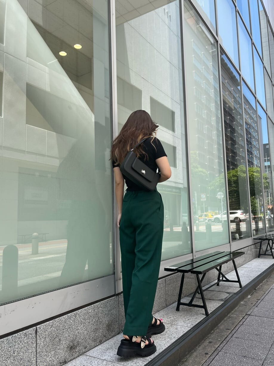 グリーン系のスラックス、ブラック系のショルダーバッグ、ブラック系のTシャツ/カットソーを着用したレディースの夏コーディネートの2枚目の写真