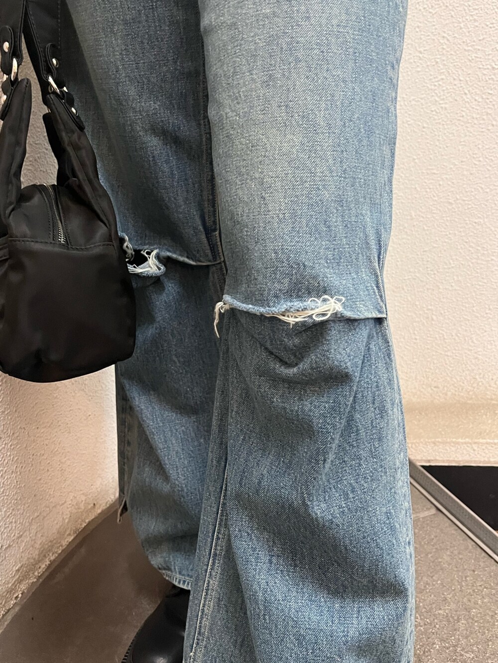 ブルー系のデニムパンツ、ブラック系のハンドバッグ、ブラック系のブーツを着用したレディースの冬コーディネートの7枚目の写真