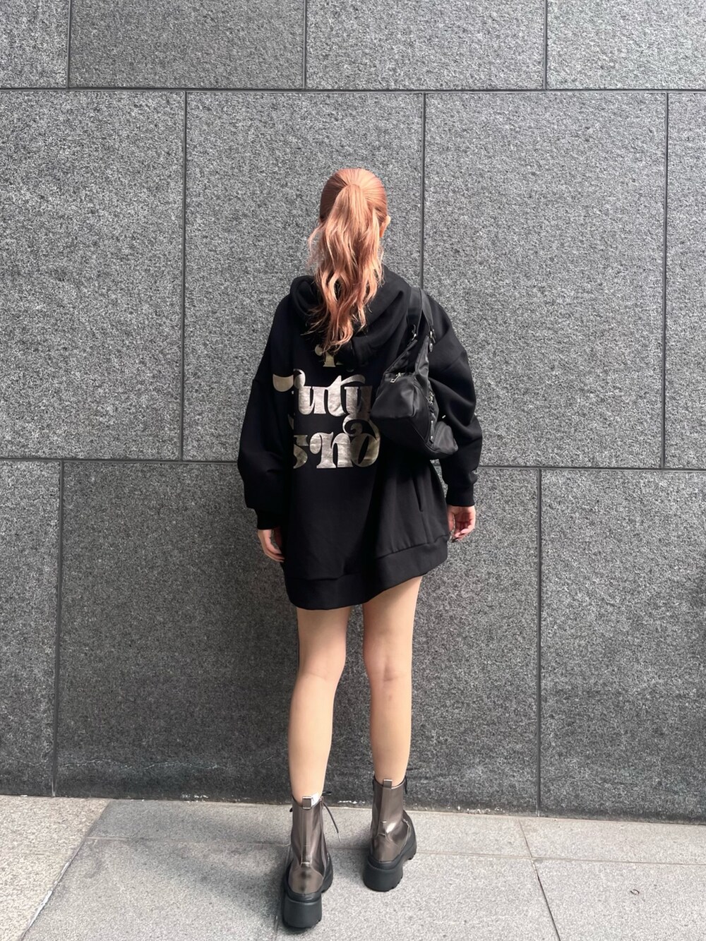 ブラック系のパーカー、ブラック系のハンドバッグ、シルバー系のブーツを着用したレディースの冬コーディネートの2枚目の写真