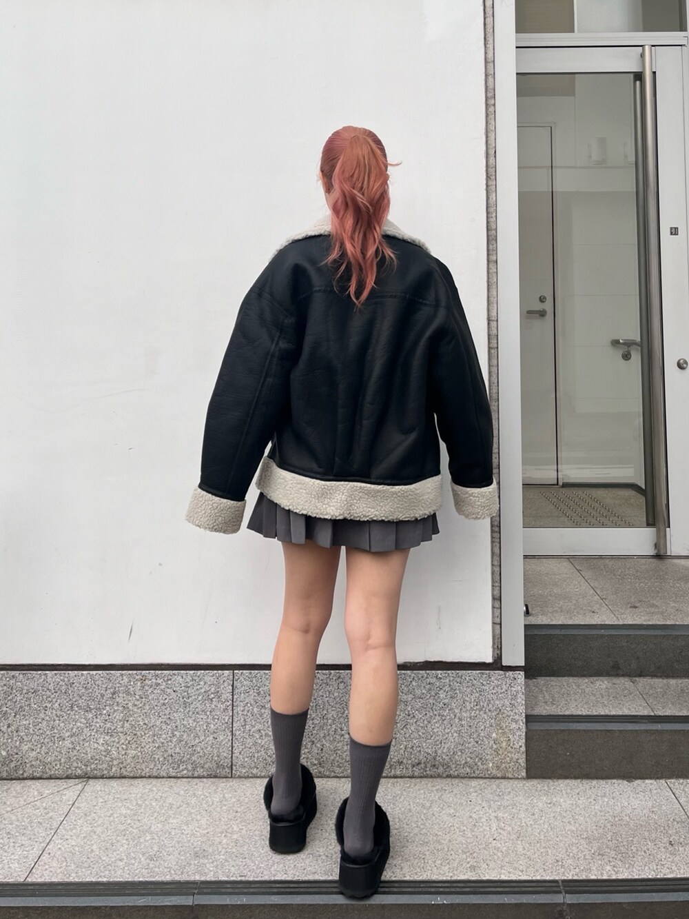 ブルー系のスウェット、グレー系のスカート、ブラック系のハンドバッグを着用したレディースの冬コーディネートの2枚目の写真