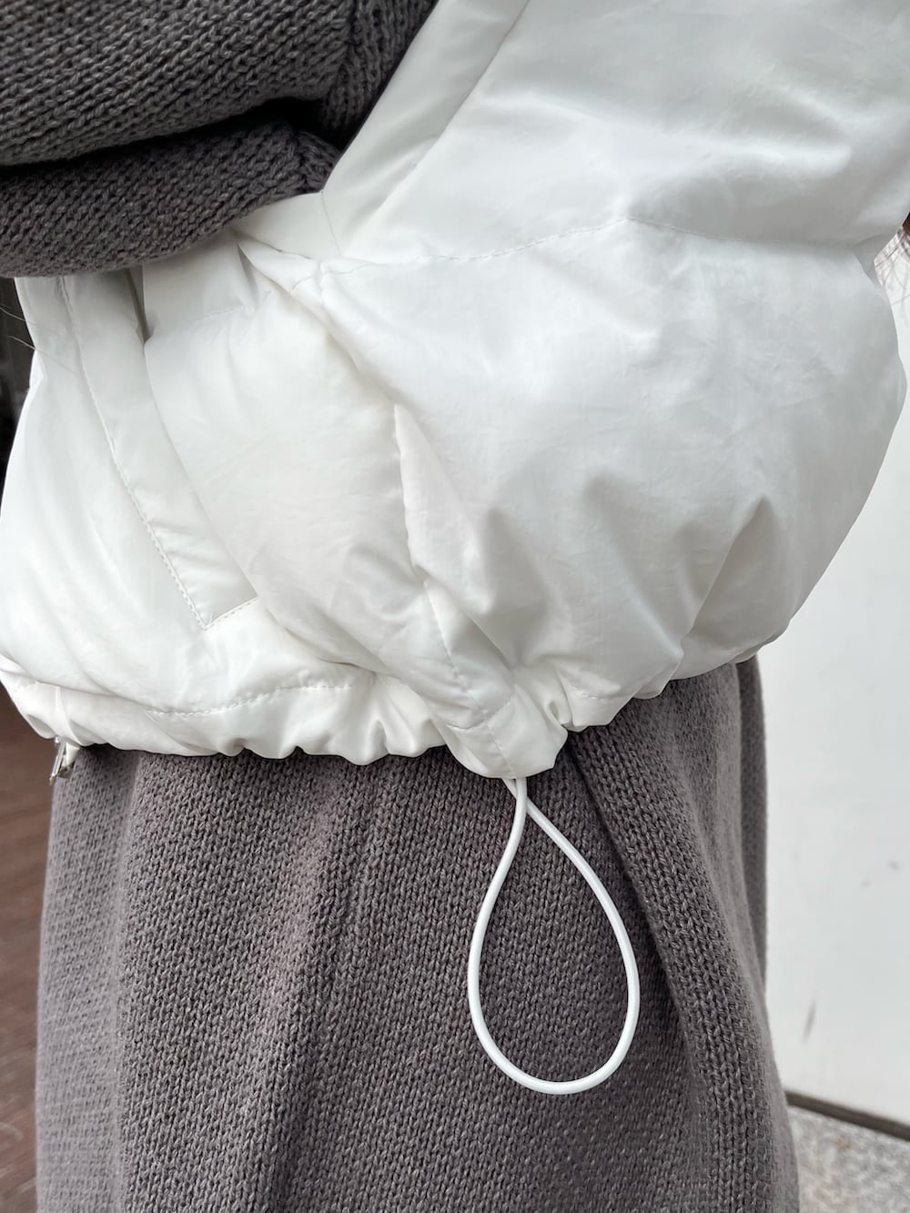 グレー系のニット/セーター、ホワイト系のショルダーバッグ、ホワイト系のブーツを着用したレディースの秋コーディネートの5枚目の写真