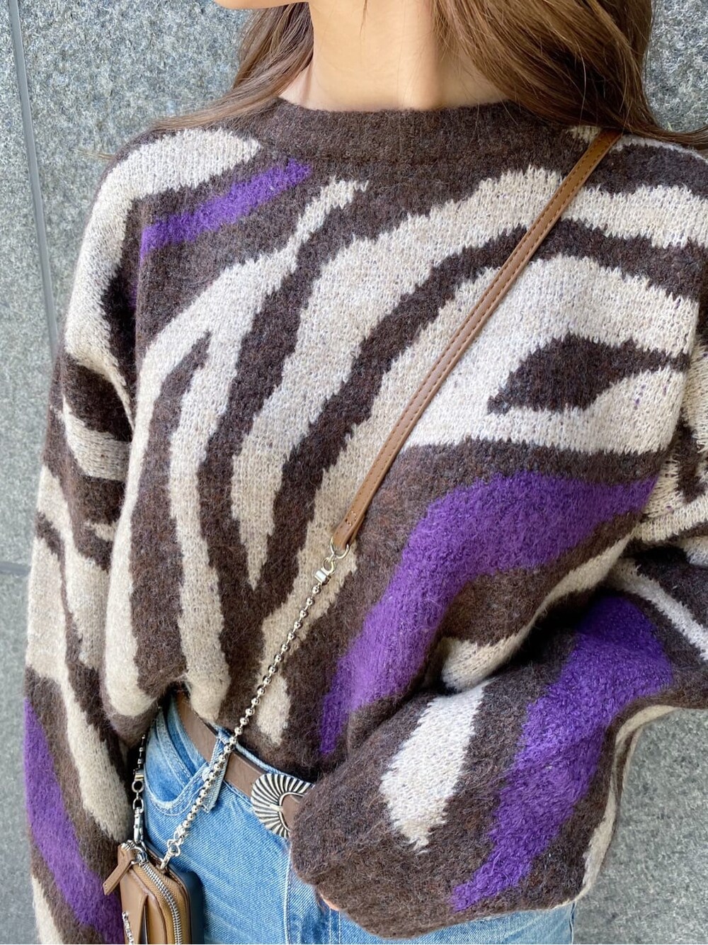 ブルー系のデニムパンツ、ブラウン系のスマホケース/カバー、ブラウン系のベルトを着用したレディースの秋コーディネートの3枚目の写真