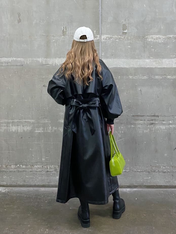 ブラック系のトレンチコート、グリーン系のボストンバッグ、ブラック系のブーツを着用したレディースの冬コーディネートの3枚目の写真