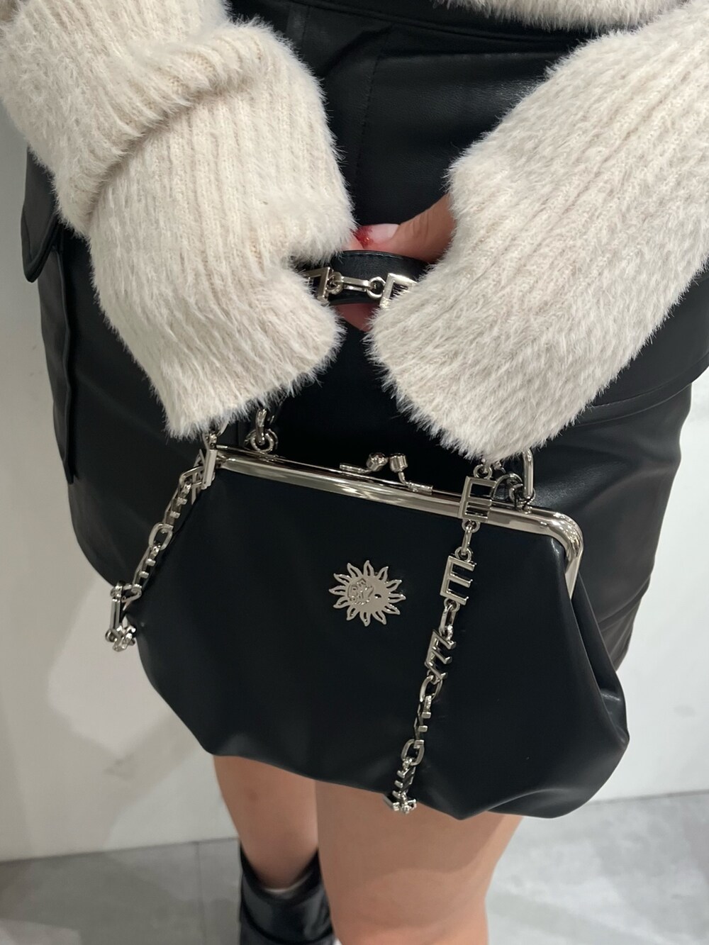 ホワイト系のニット/セーター、ブラック系のスカート、ブラック系のショルダーバッグを着用したレディースの冬コーディネートの4枚目の写真