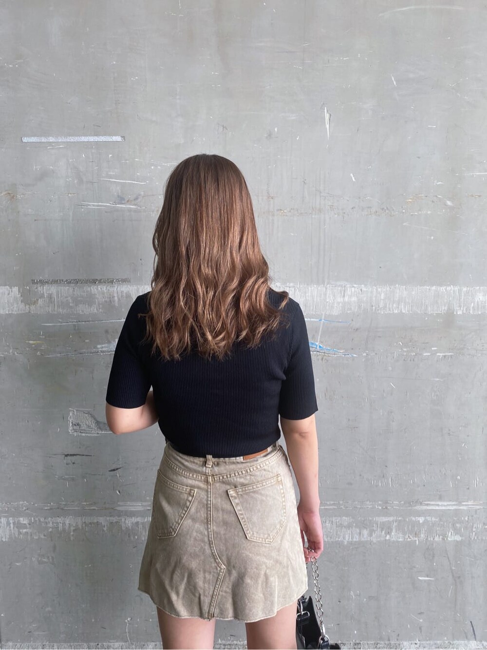 ベージュ系のデニムスカート、ブラック系のサンダル、ブラック系のTシャツ/カットソーを着用したレディースの夏コーディネートの5枚目の写真