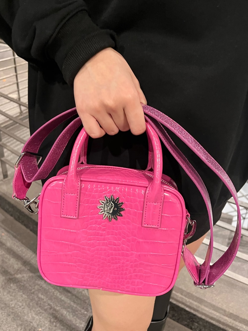 ブラック系のスウェット、ピンク系のショルダーバッグ、ブラック系のブーツを着用したレディースの冬コーディネートの7枚目の写真