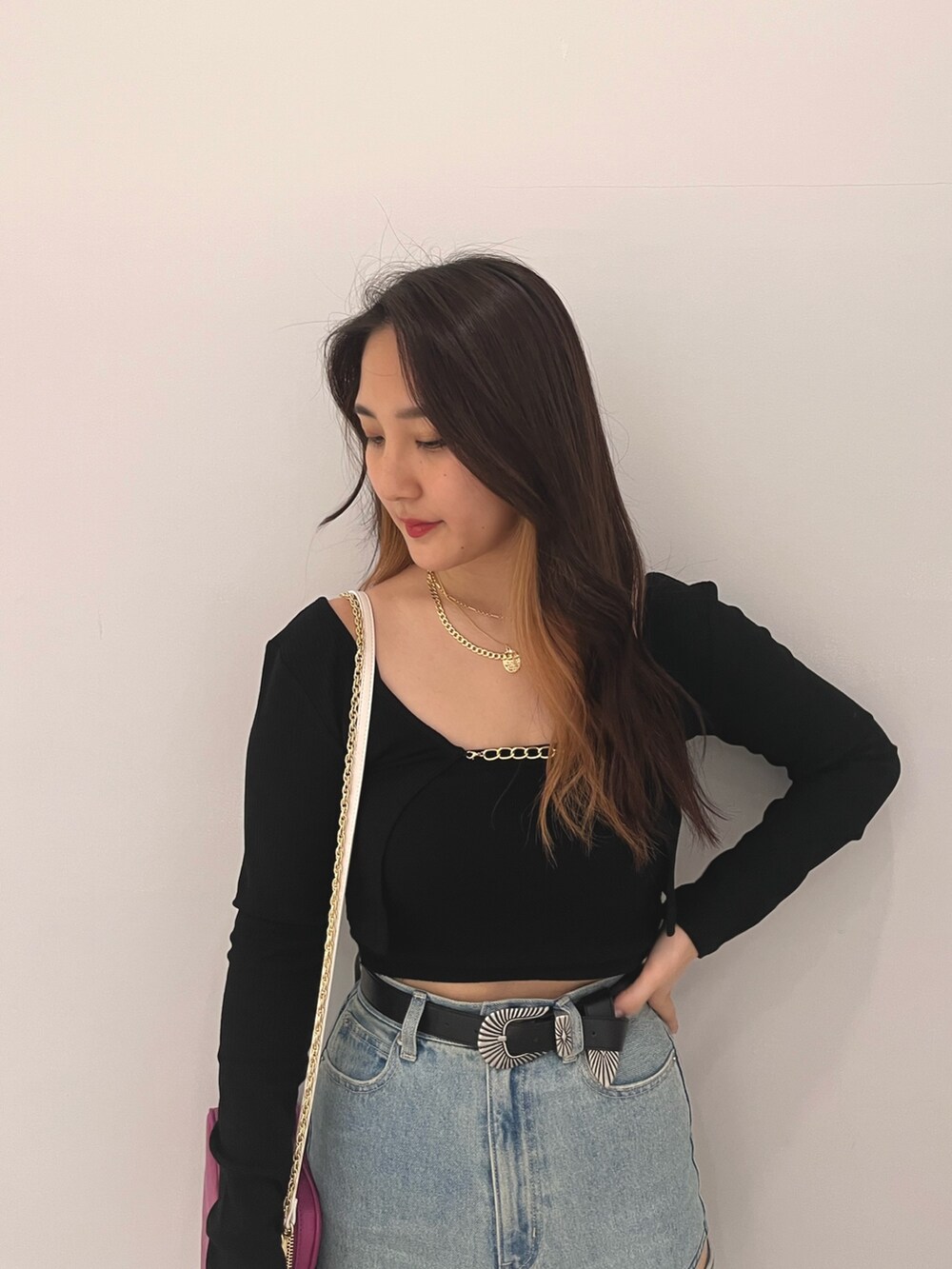 ブルー系のデニムパンツ、ブラック系のニット/セーター、パープル系のショルダーバッグを着用したレディースの春コーディネートの3枚目の写真