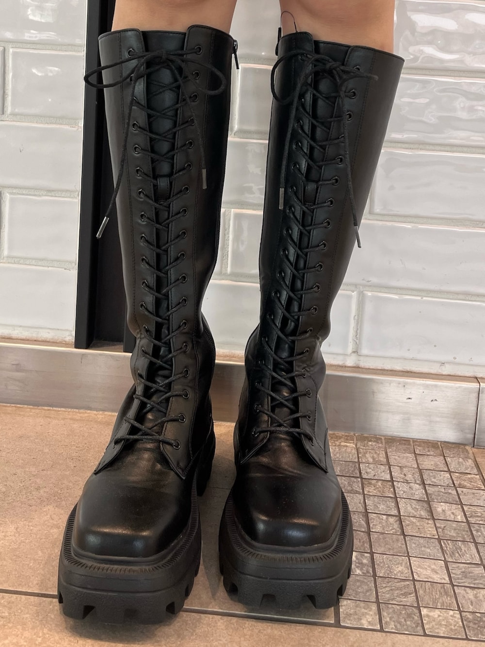 ブラック系のブーツ、ブラック系のナイロンジャケット、ホワイト系のショルダーバッグを着用したレディースの秋コーディネートの4枚目の写真