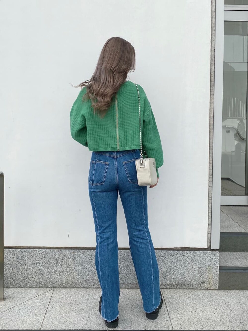 ブラック系のブーツ、ホワイト系のショルダーバッグ、グリーン系のニット/セーターを着用したレディースの冬コーディネートの2枚目の写真