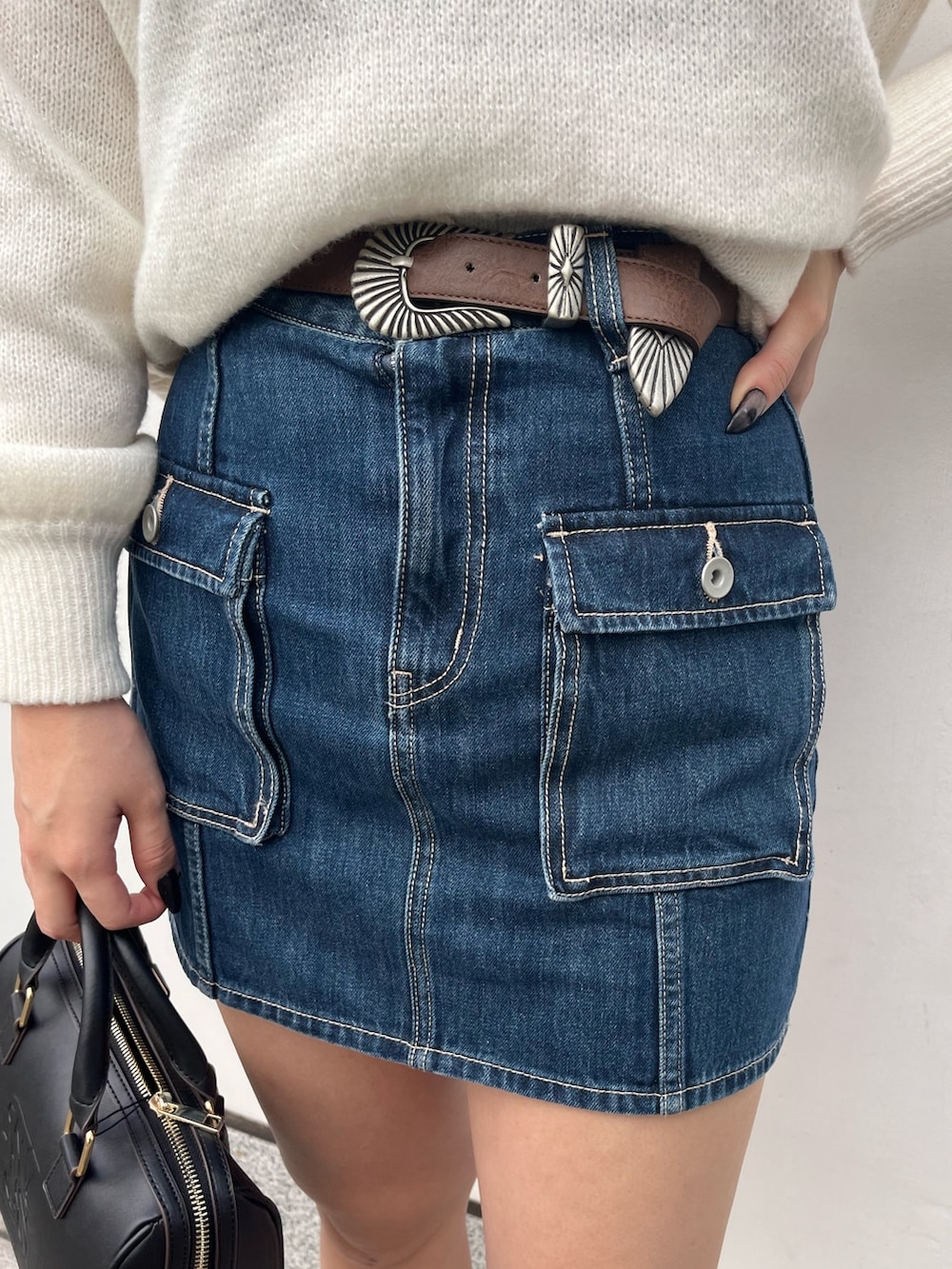 ホワイト系のニット/セーター、ブルー系のデニムスカート、ブラック系のボストンバッグを着用したレディースの冬コーディネートの5枚目の写真