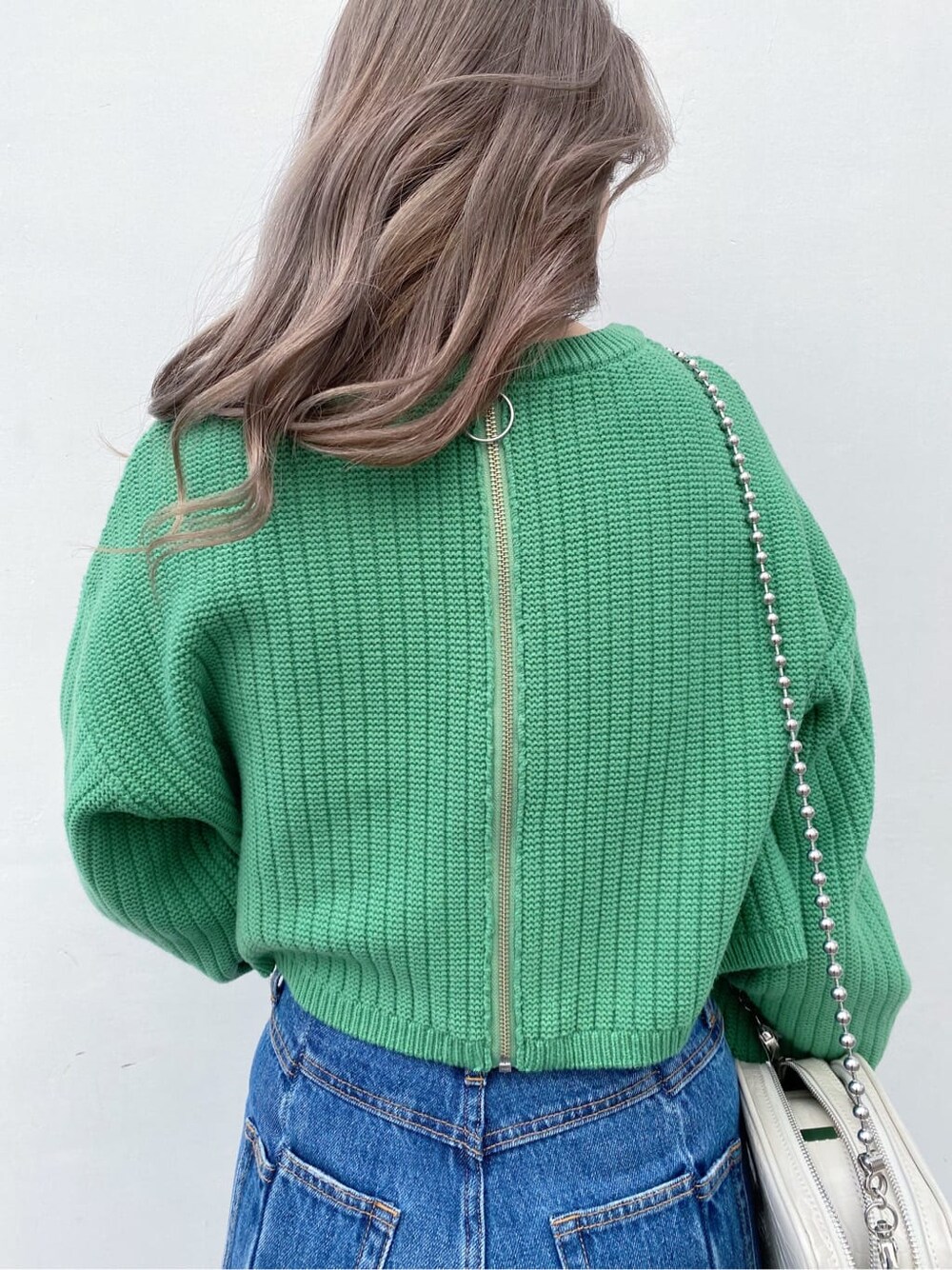 ブラック系のブーツ、ホワイト系のショルダーバッグ、グリーン系のニット/セーターを着用したレディースの冬コーディネートの4枚目の写真