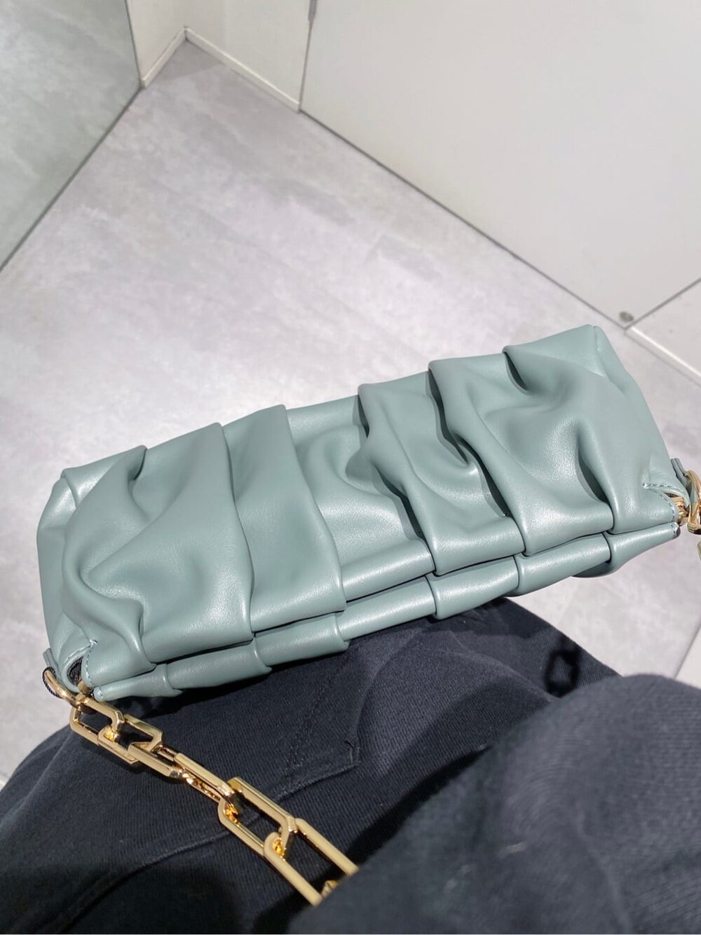 ブラウン系のデニムパンツ、ブラック系のパーカー、グリーン系のショルダーバッグを着用したレディースの秋コーディネートの5枚目の写真