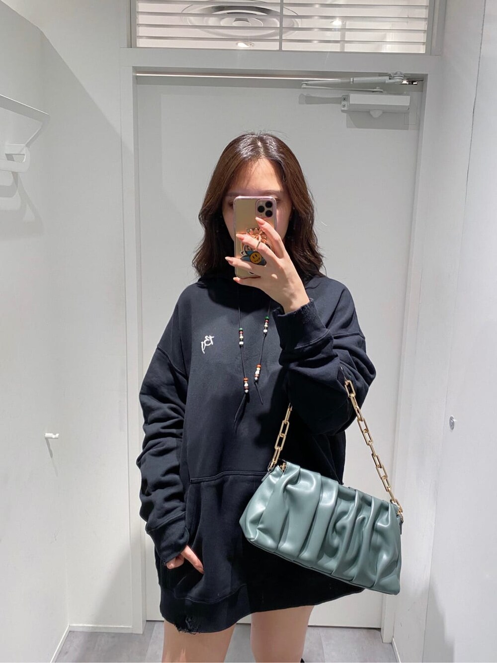 ブラウン系のデニムパンツ、ブラック系のパーカー、グリーン系のショルダーバッグを着用したレディースの秋コーディネートの3枚目の写真