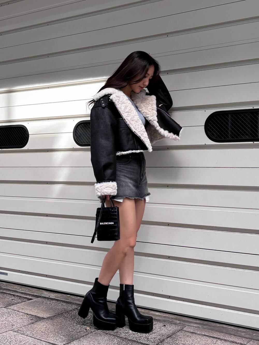 ブラック系のブルゾン、グレー系のニット/セーター、ブラック系のデニムスカートを着用したレディースの冬コーディネートの2枚目の写真