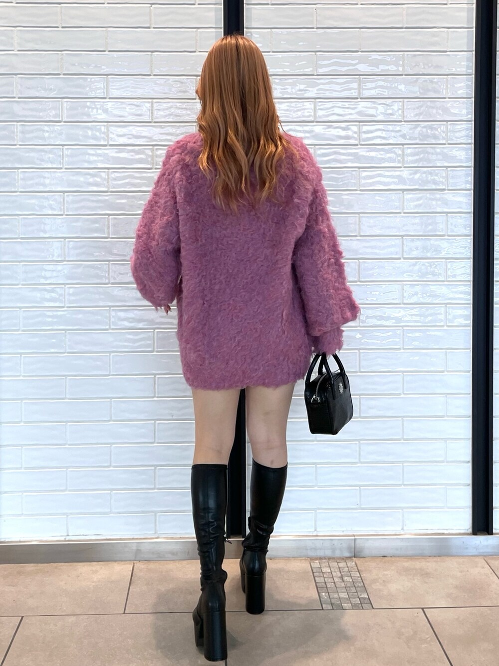 ピンク系のカーディガン/ボレロ、ブラック系のショルダーバッグ、ブラック系のブーツを着用したレディースの冬コーディネートの3枚目の写真